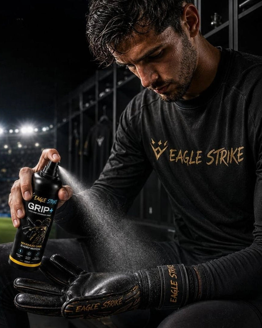 A man in a black long-sleeve athletic shirt and black goalkeeper gloves sprays a black grip spray bottle onto his glove. The bottle label reads 'EAGLE STRIKE GRIP'.